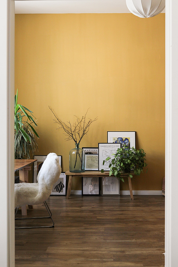 Minimalist home office with framed art and cheery golden painted accent wall